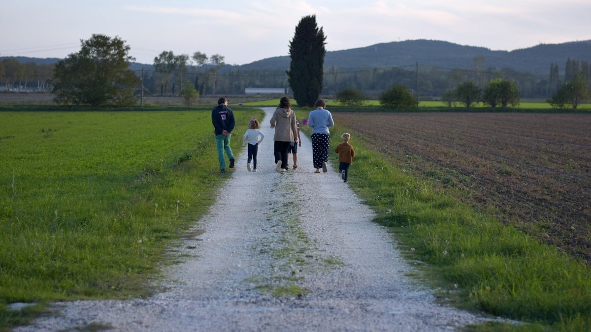 a group of people walking on a dirt road in a field